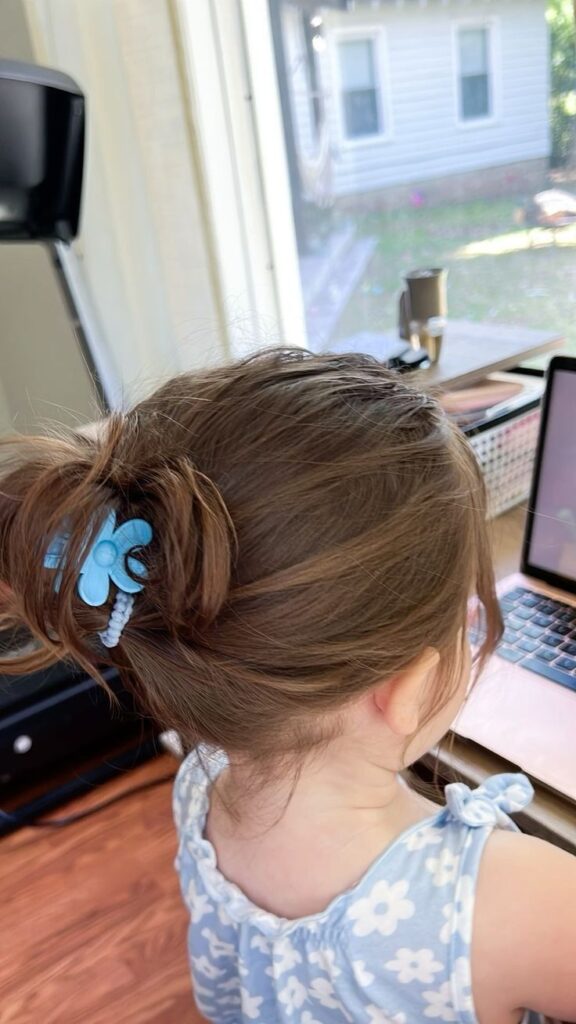 A little white girl with hair  in a messy bun. With a  claw clip holding everything together 
