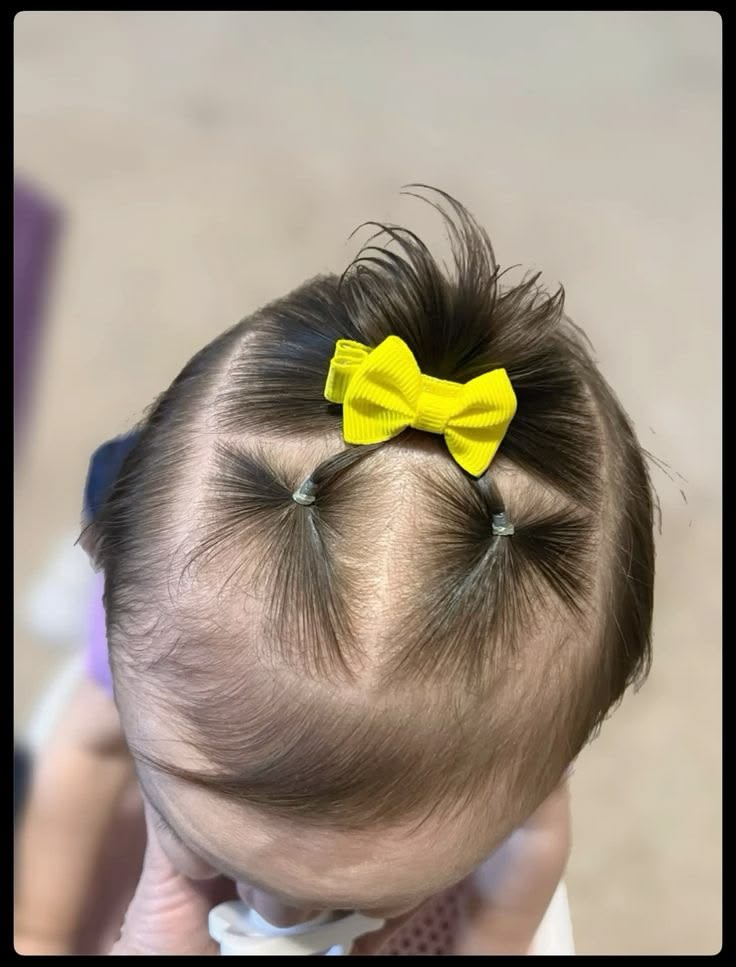 A toddlers hair styled with a yellow bow