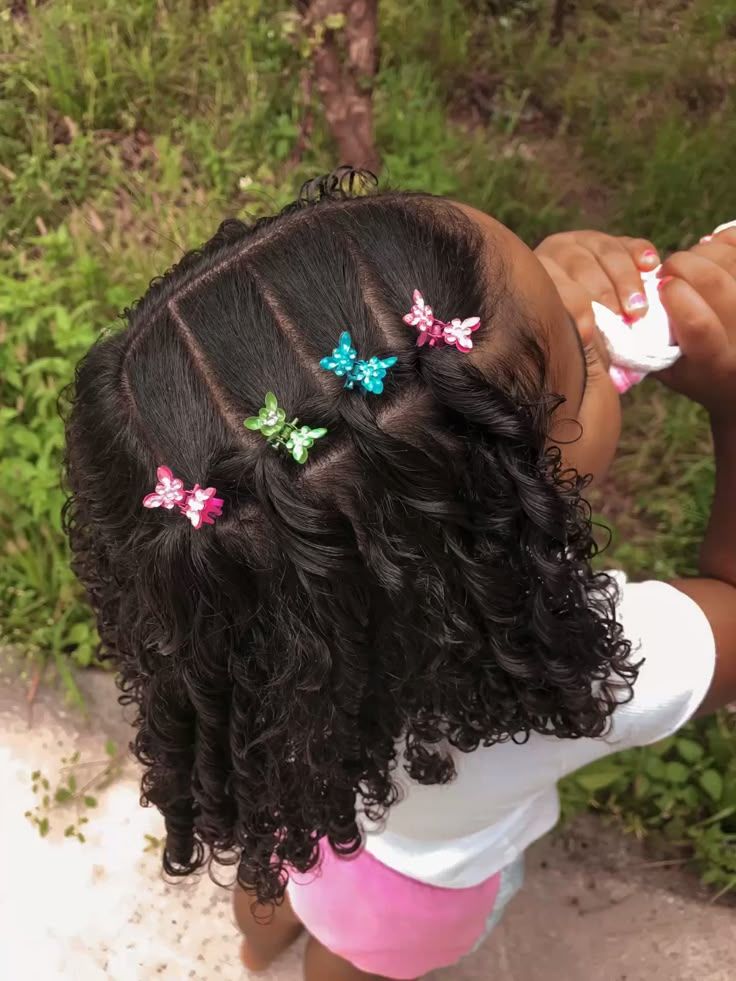 A little girl standing outside with a cute side sweep hairstyle with a colorful decorative clip