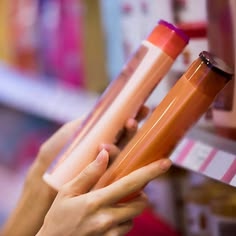  a hand holding two conditioner comparing the labels to cose which is better