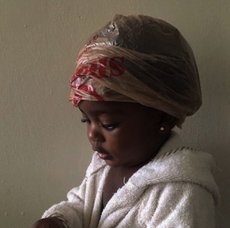 Child wearing a plastic deep conditioning cap wrapped in a towel