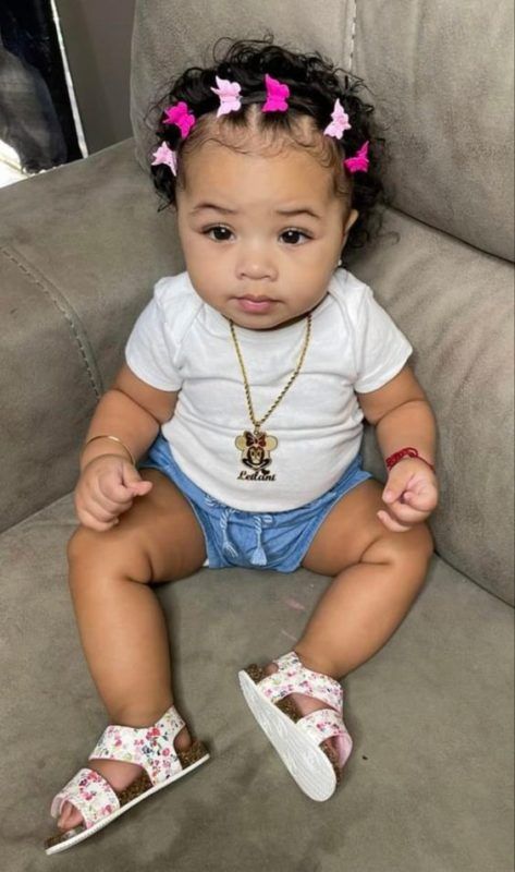 Baby girl with curly hair styled with small pink bow clips across the crown