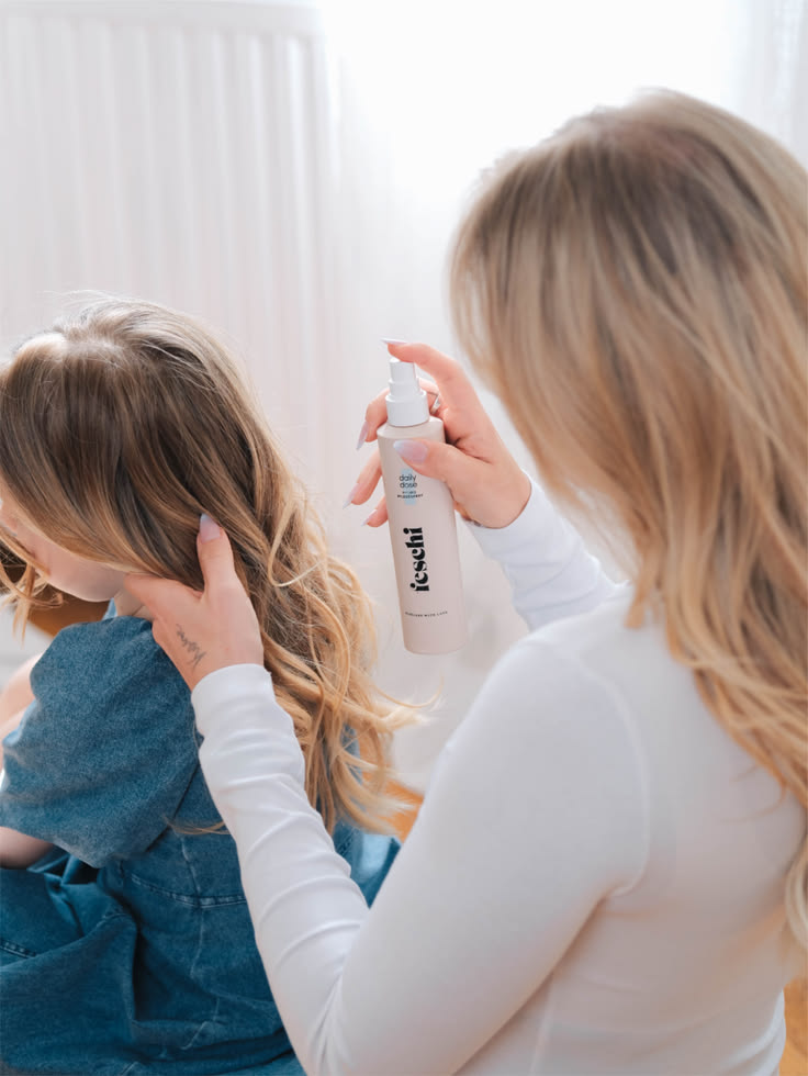 Parent spraying product into child's hair