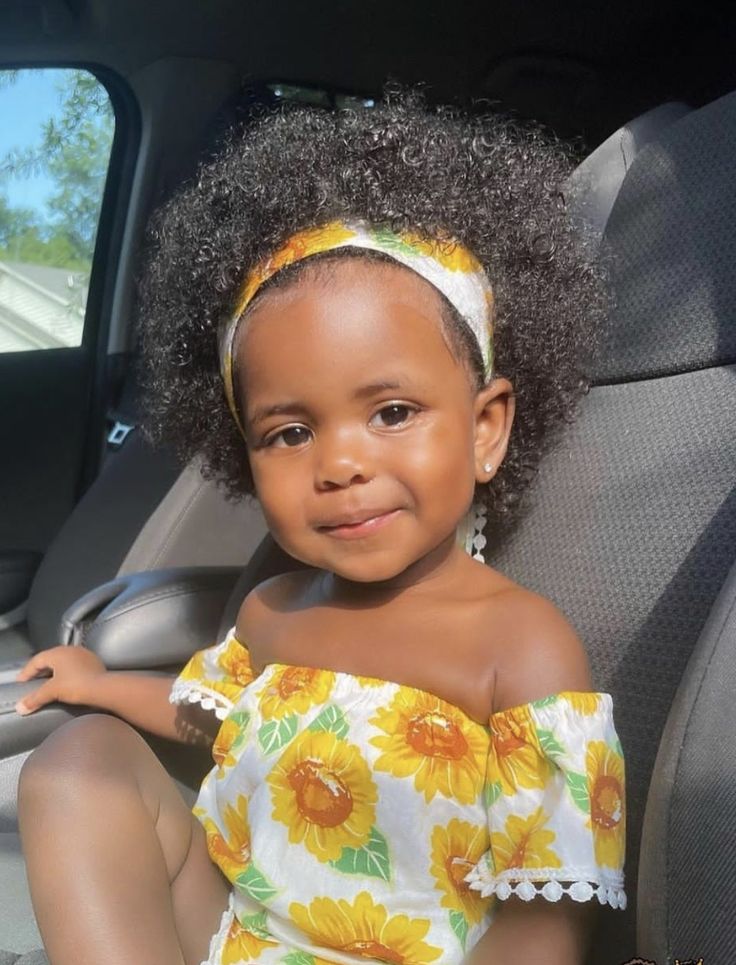 Toddler with a full curly afro and yellow patterned headband