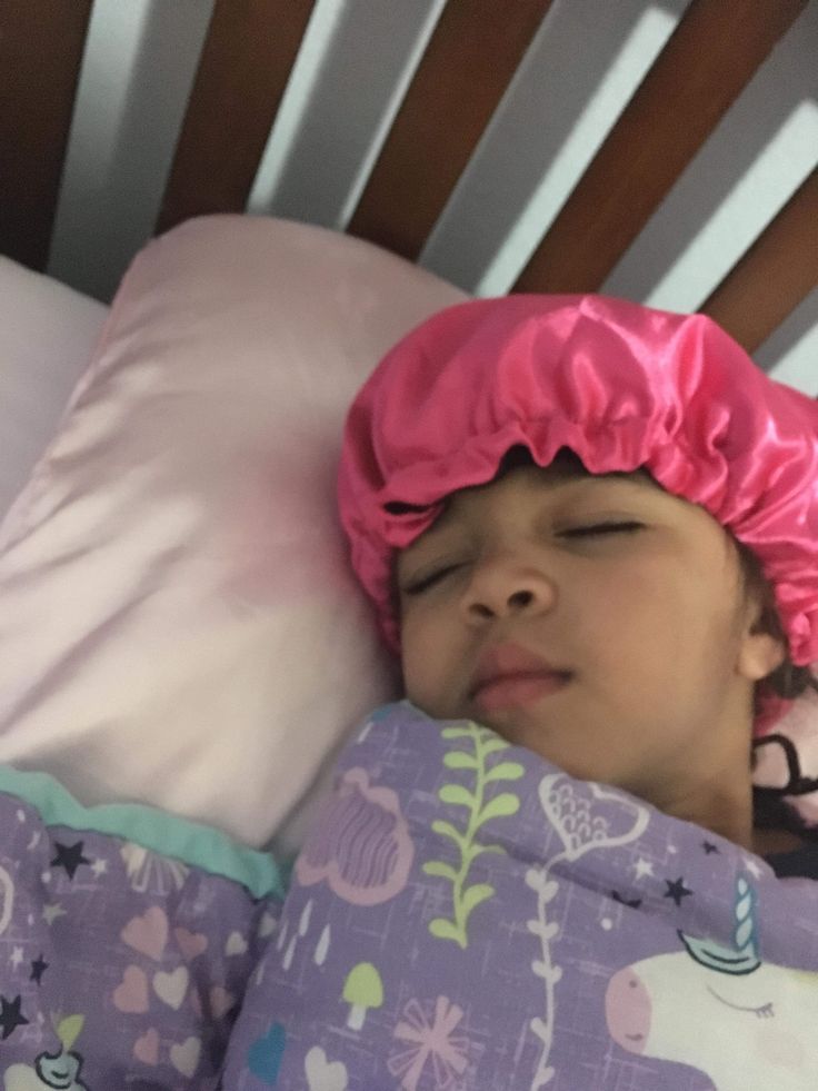 Child sleeping in a pink satin bonnet