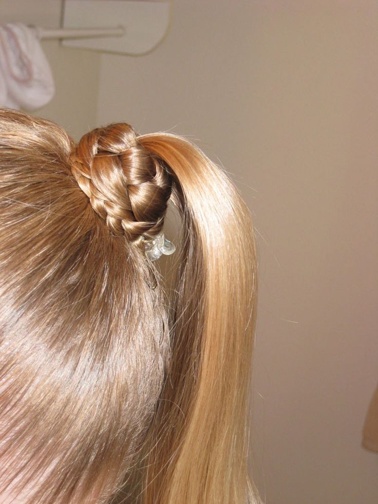 A girls blond hair ponytail with a braided wrap around it.