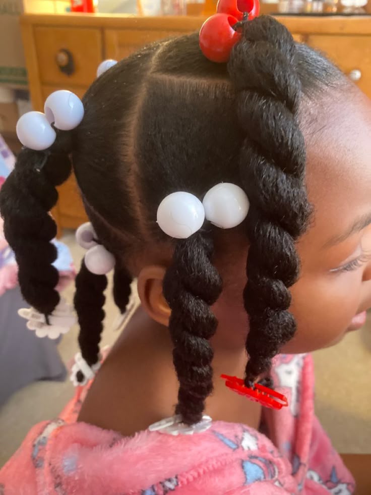 Young girl with hair styled in two chunky twisted pigtails finished with round beads