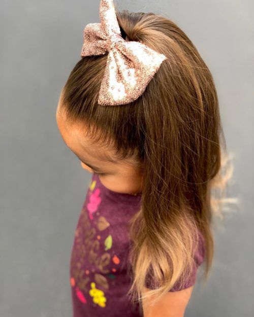 Young girl with straight hair styled in a half-up style with a decorative clip