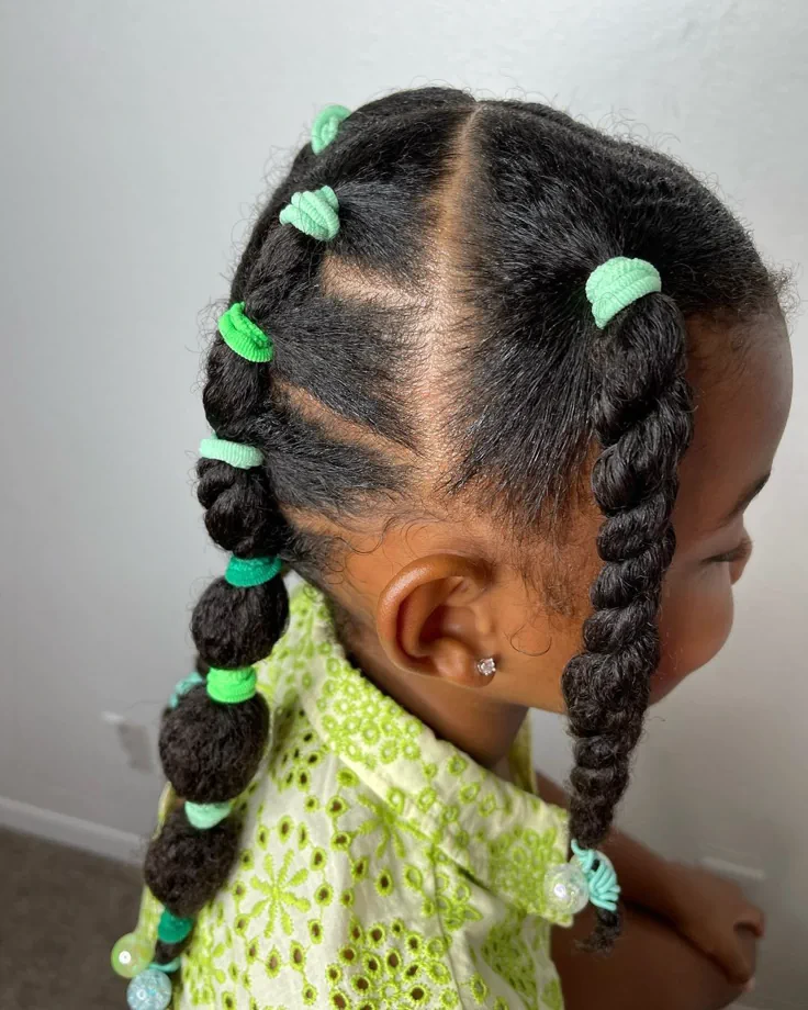 Young girl with hair styled in multiple sectioned twists gathered into two pigtails with colorful hair ties