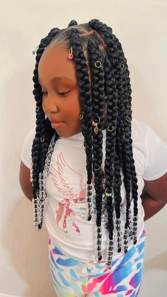 Kids knotless braids styled with gold hair cuffs for a polished look.