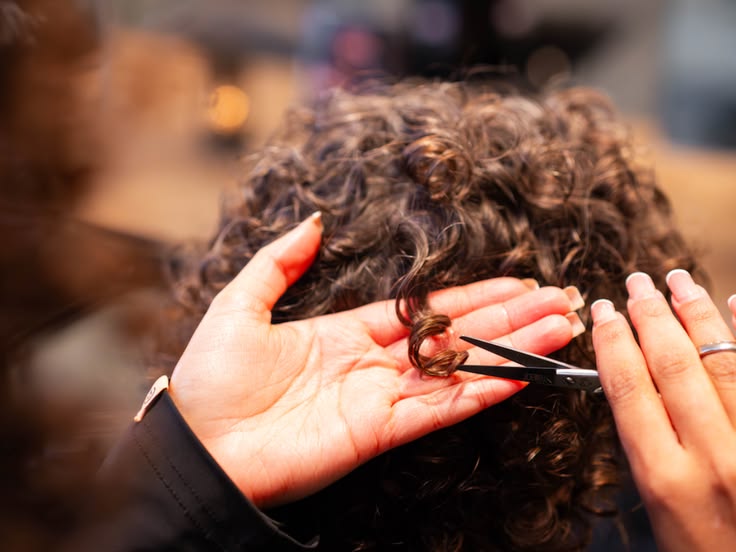 A stylist  trimming a child's curly hair in a saloon