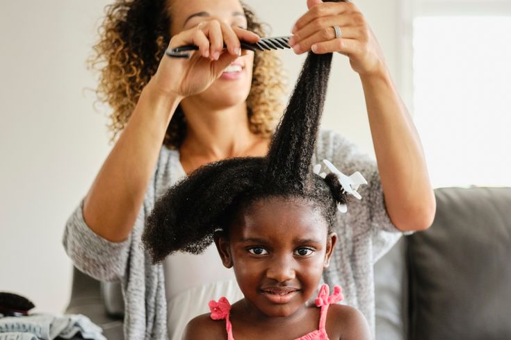 Detangling curly and coily kids' hair with a wide-tooth comb.