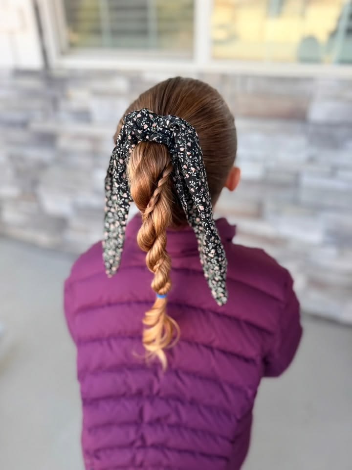 A young girl with a scarf wrapped ponytail