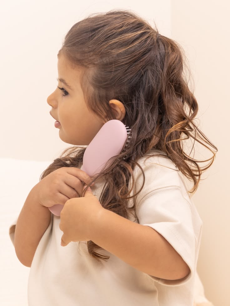 A cute little girl brushing her type 3 hair with detangling brush