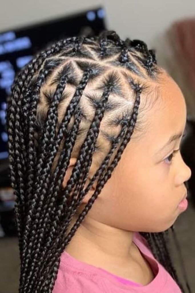  A child wears classic knotless braids parted into small triangle sections, showing a smooth, tension-free root.