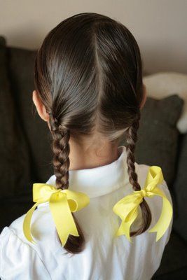 young girl with her back facing the camera showing he double pigtails with a yellow bow