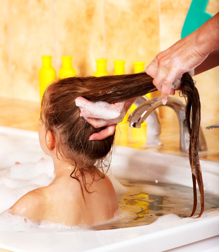 Child washing hair in bubble bath.