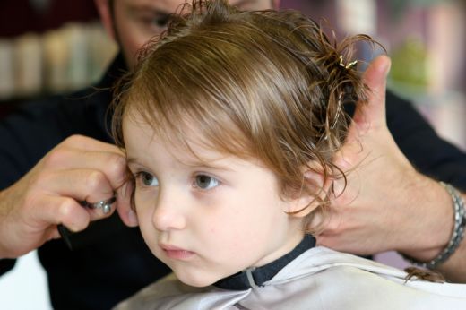 Toddler getting a haircut at home with wet hair sectioned for trimming