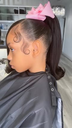 Beautiful young girl with a ponytail, curly edges, a side prat in the front, and a pink bow.