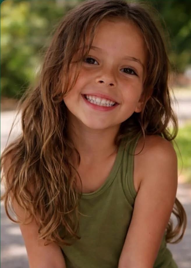 Young girl with fine, tousled type 2 wavy hair showing natural frizz and loose waves, outdoors in humid weather.