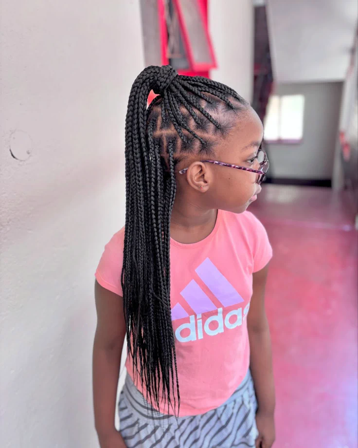 A child wears medium box braids gathered into a half ponytail, 