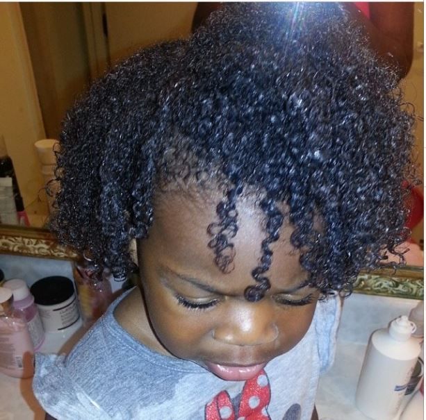Child's curly hair looking moisturized and defined after applying leave-in conditioner and oil.