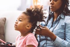 Mom styling daughter's curly hair at home