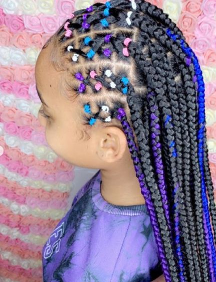 A child wears braids sectioned with colorful rubber bands in a geometric pattern, finished with blue and purple braided extensions.
