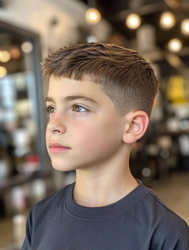 Boy with a textured crop hairstyle, short choppy layered top and low fade blending into the sides.
