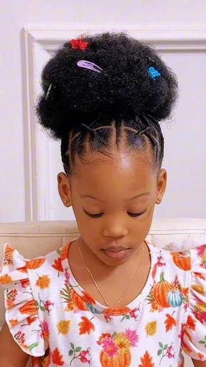 Little girl with threaded and twisted high puff and rainbow hair clips."