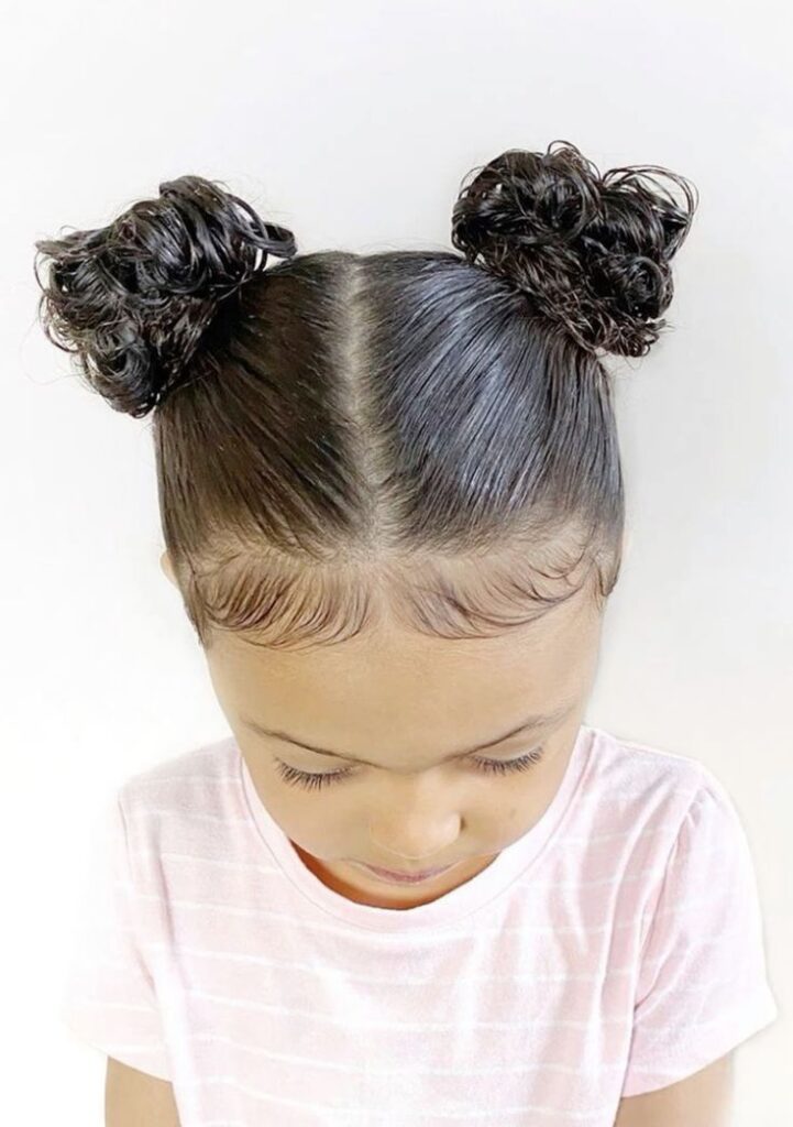 Young girl with curly hair styled in two space buns
