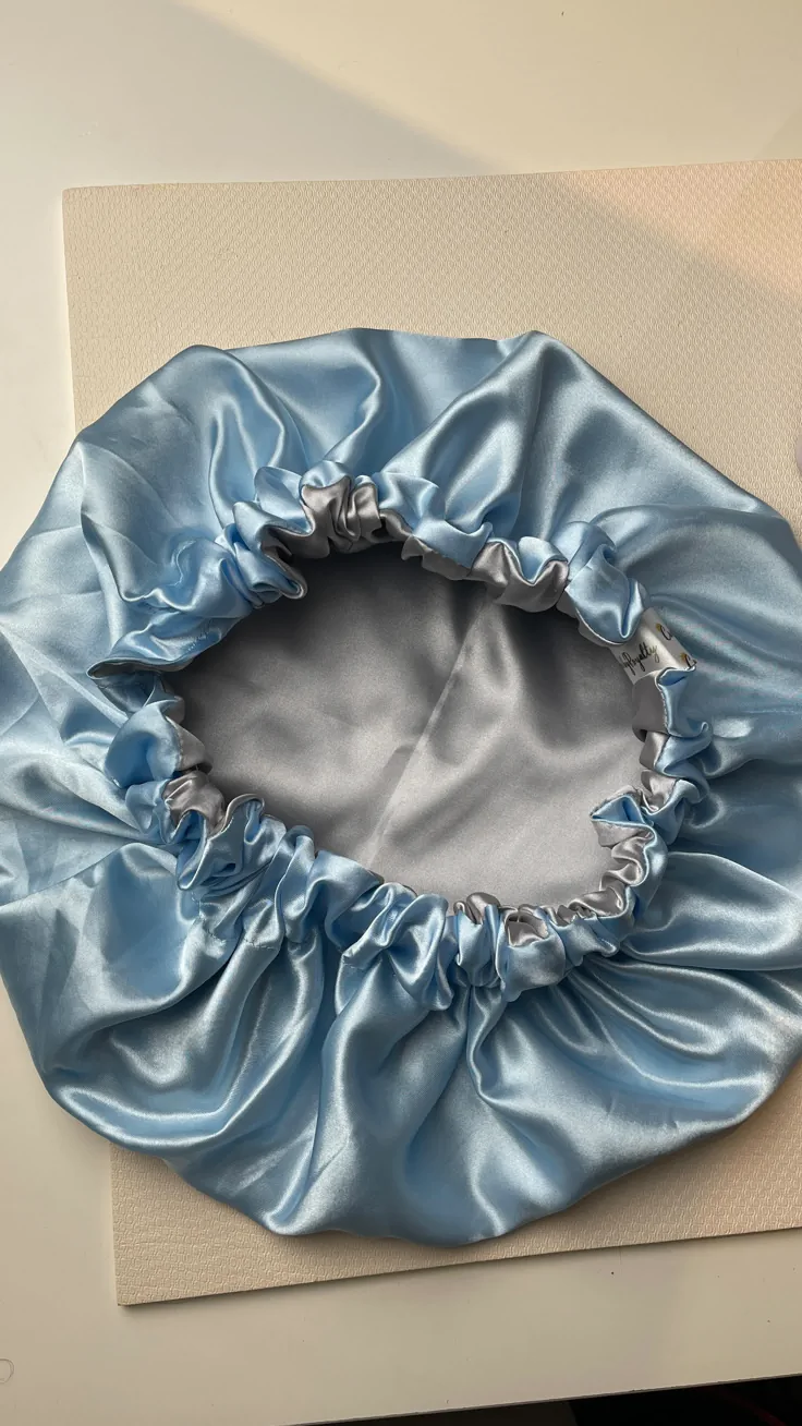 Blue satin bonnet used to protect a child's hair moisture overnight and prevent breakage while sleeping.