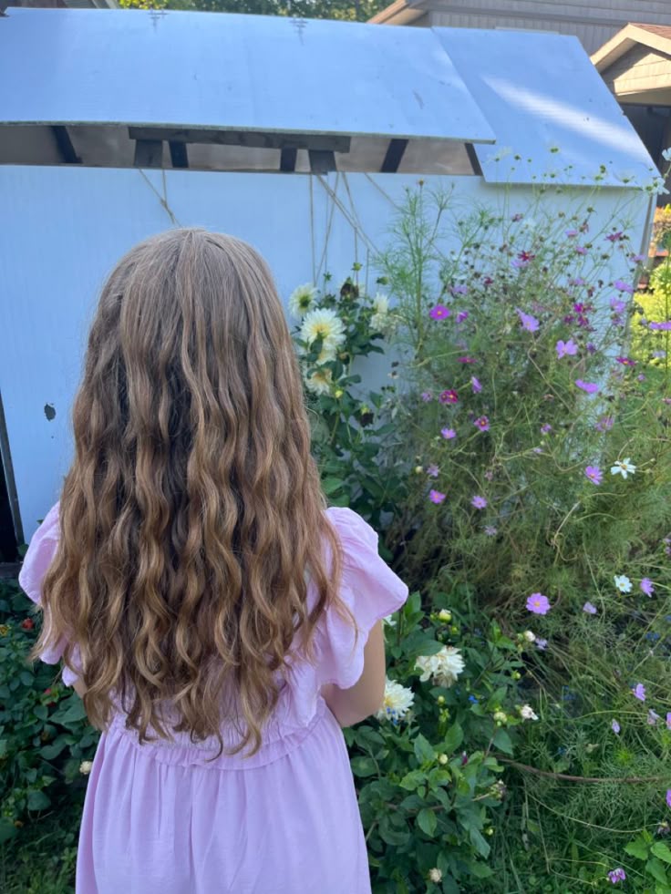 A young girl with her back facing the camera with a wavy long hair