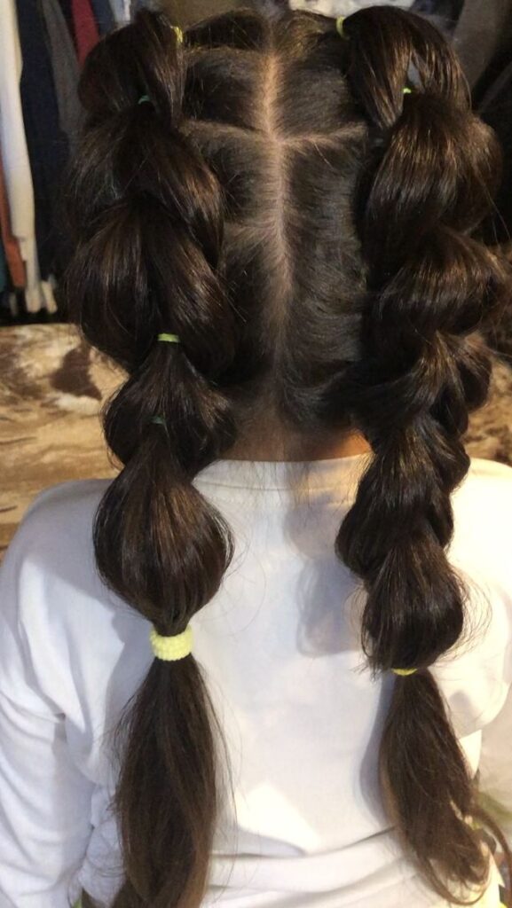 Young girl with curly hair styled in two braided pigtails