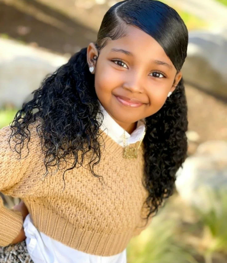 Cute young girl smiling with her beautiful curled ponytail with a side part