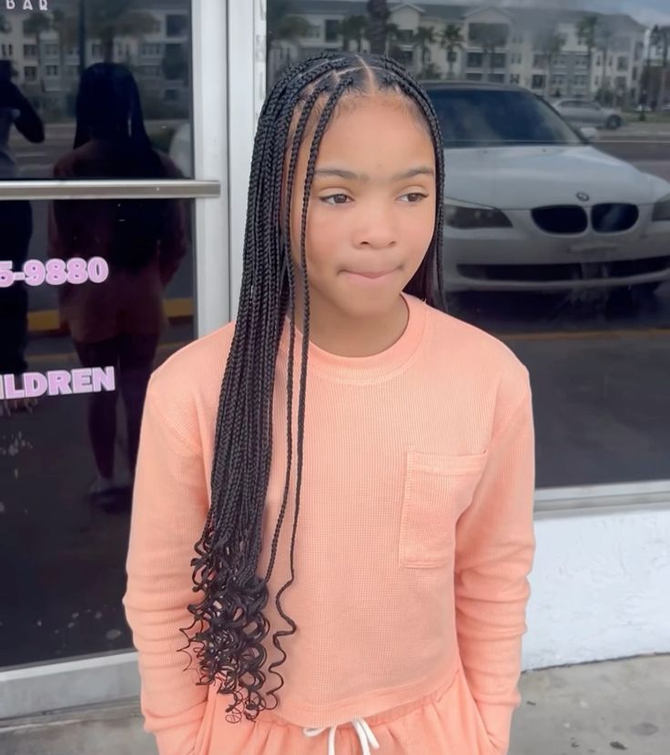 A child wears small, tightly-parted knotless braids with curled ends, creating a full, voluminous look.