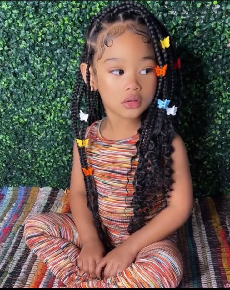 Cute knotless braids for kids decorated with colorful butterfly hair clips.
