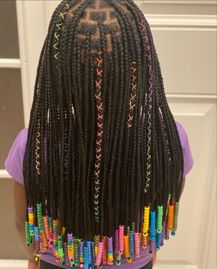 Young girl wearing knotless braids with colorful ribbon accents woven into the braids.