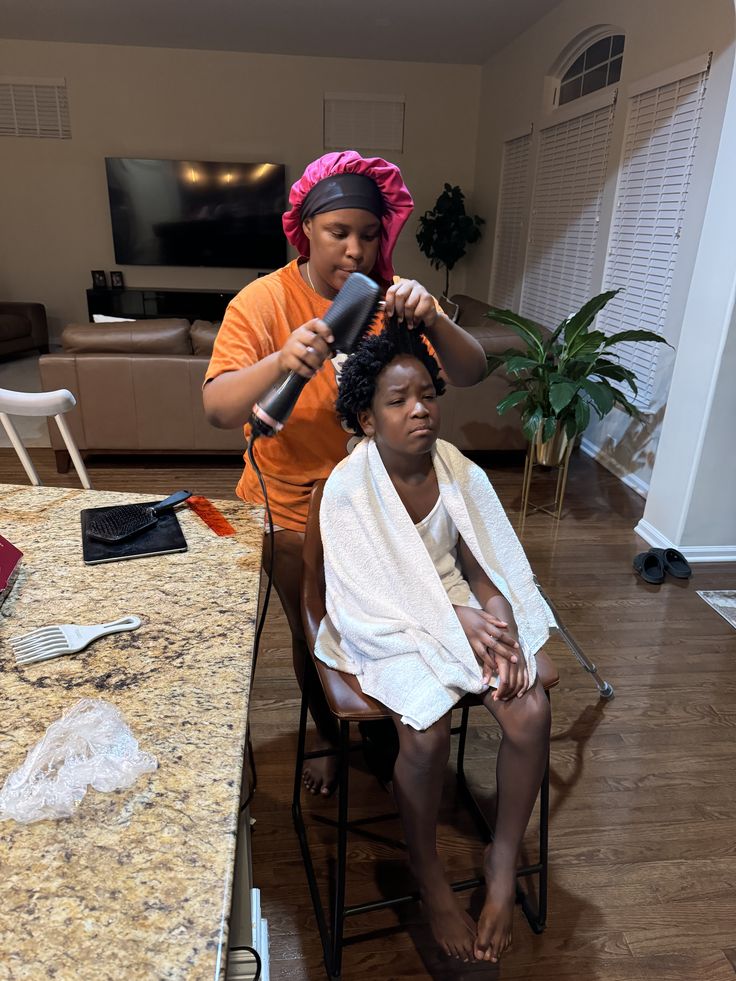 A parent detangling a child's coily hair before braiding
