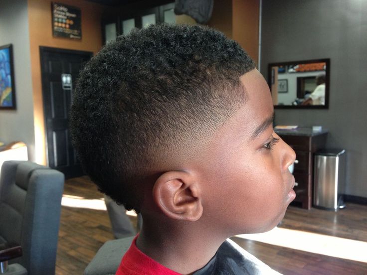 Boy with a low fade haircut, subtle taper near the ear and short natural coily hair on top.