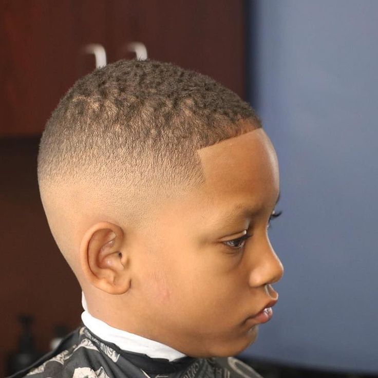 Boy with a high fade haircut, dramatic taper starting near the temple down to skin with short even hair on top.