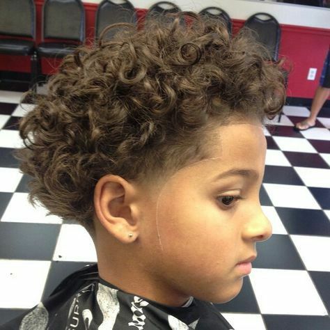 Boy with a blowout fade haircut, full rounded curls on top and sides faded down to skin.