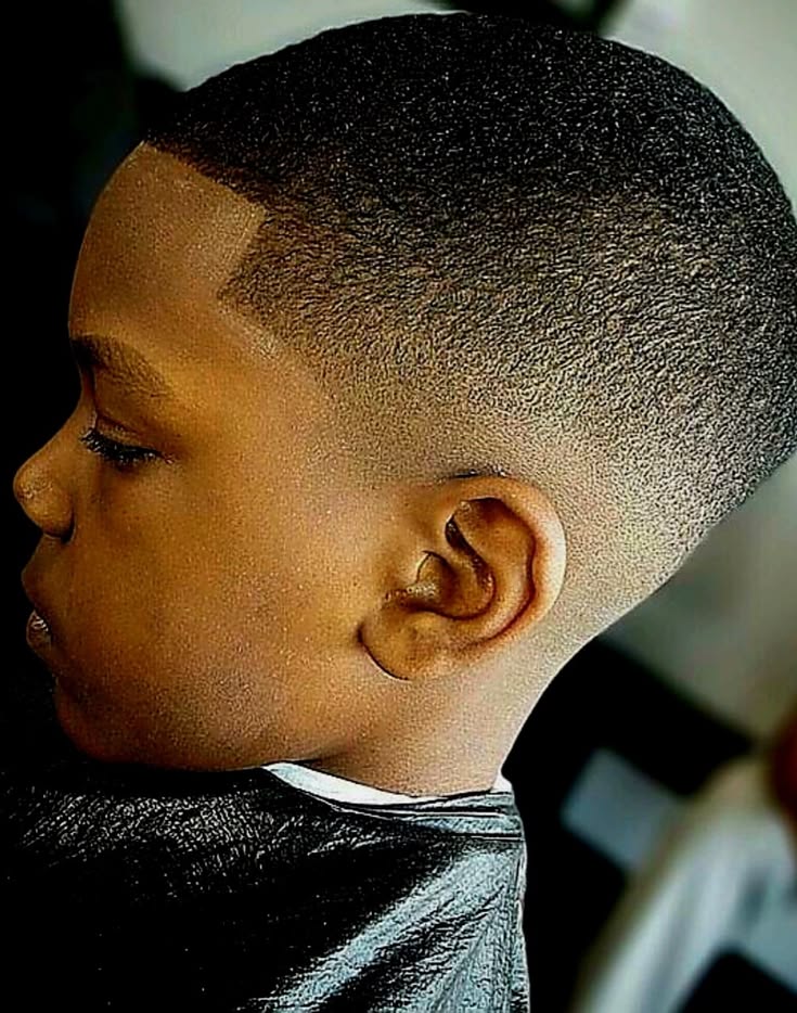 Boy with a drop fade haircut, fade line curving down and rounding in behind the ear.