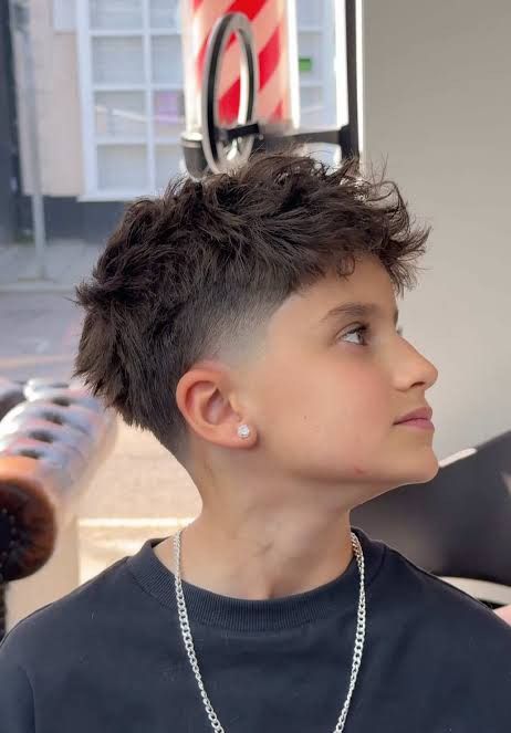 Boy with a French crop haircut, choppy textured top and light fade blending into the sides.