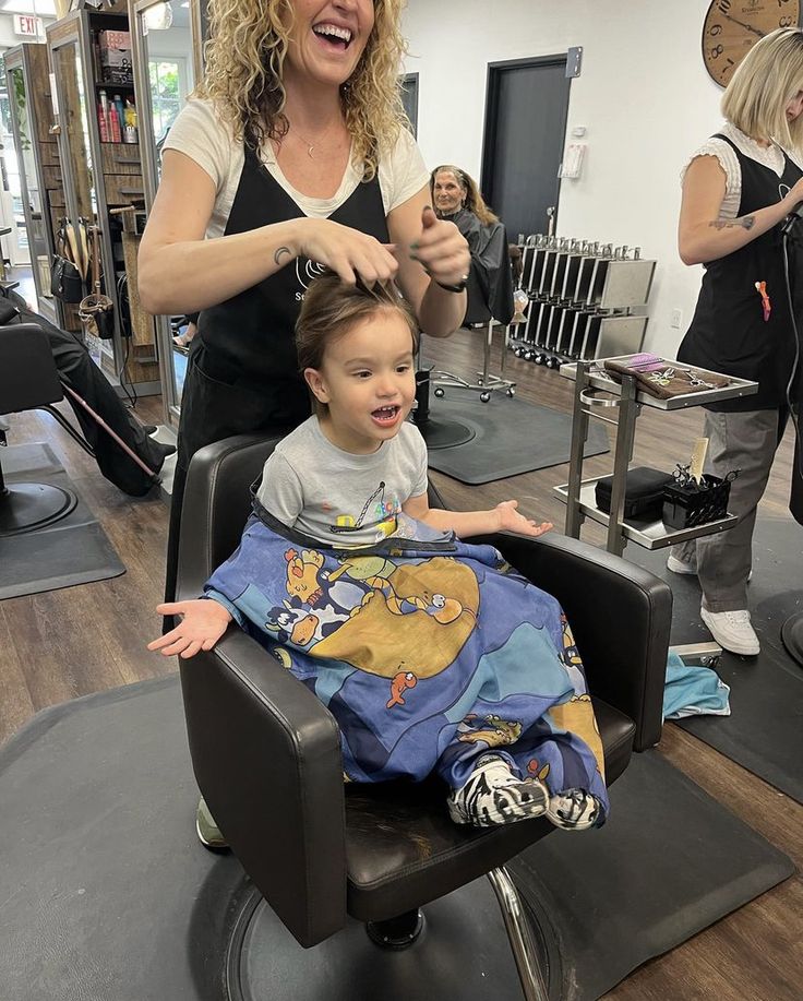 Happy toddler with a kid-friendly hairstylist at the salon