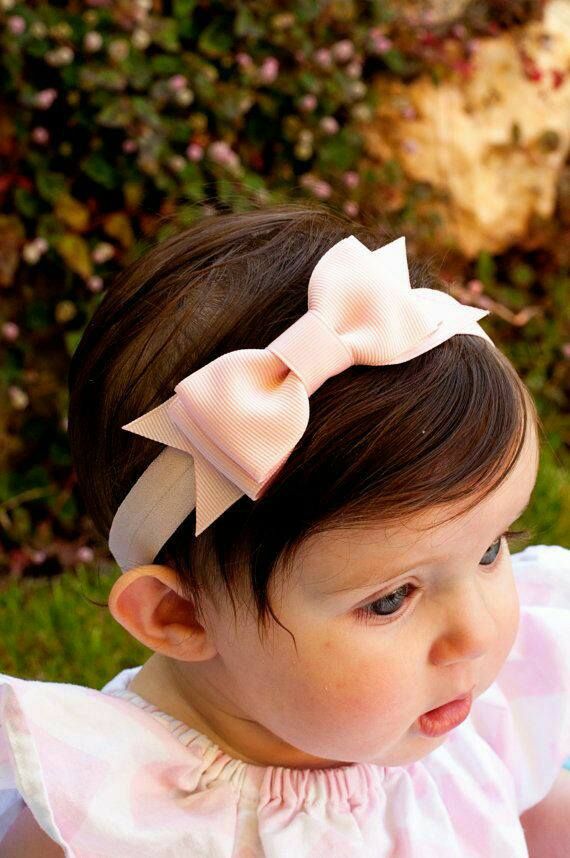 A cute toddler with a peach coloured fabric bow headband.