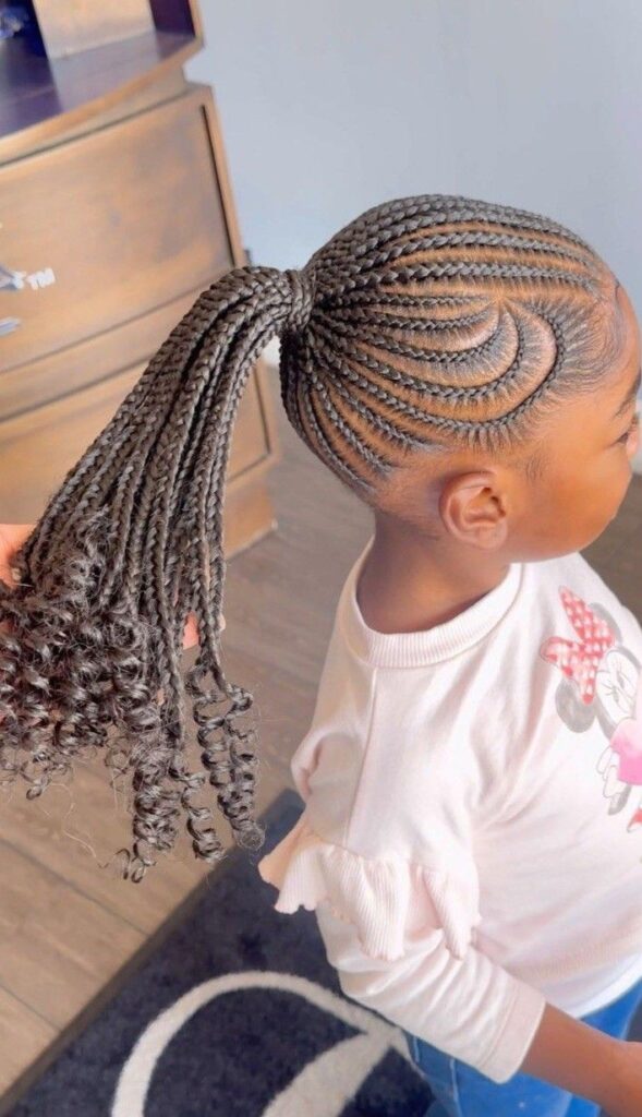 Little girl wearing feed in braids gathered into a  low ponytail.