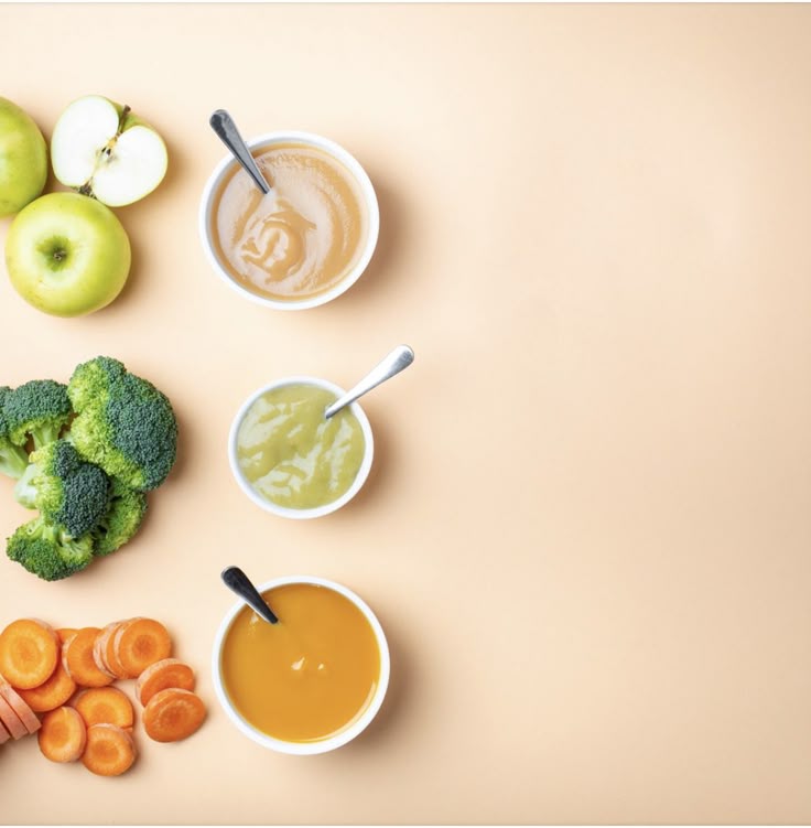 Overhead view of apple, broccoli, and carrot alongside bowls of matching baby purees, representing a varied diet that supports healthy hair growth."