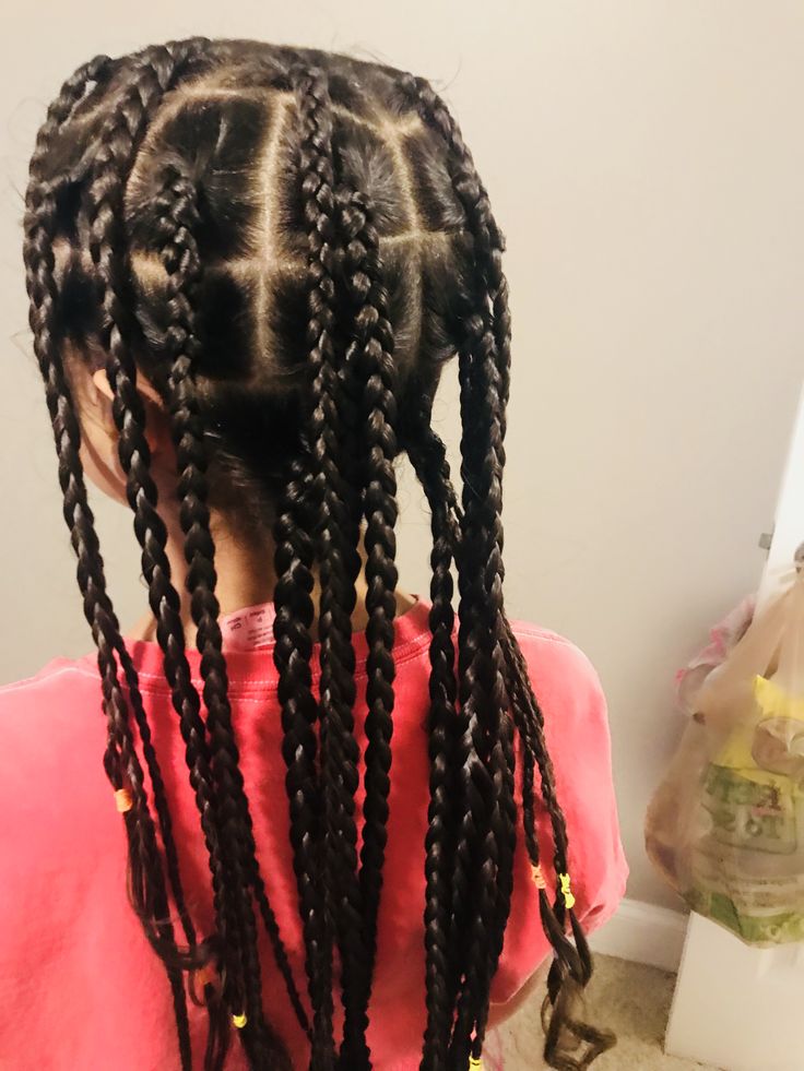 Young girl with scanty box braid and colorful bands at the end to secure it.