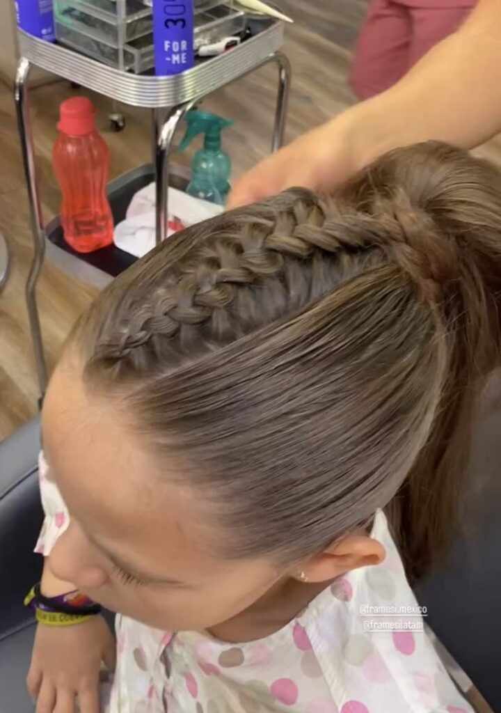 A white girl with a single Dutch braid put into her ponytail